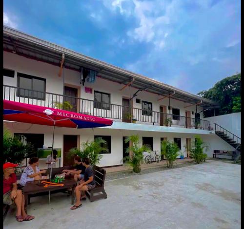 a group of people sitting at a table outside of a building at Adam's Hotel Apartment in Pandi