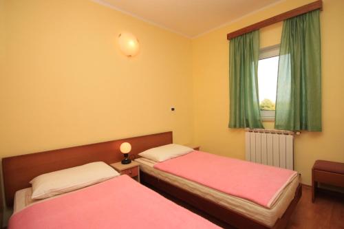 a bedroom with two beds and a window with green curtains at Apartments with a parking space Tar, Porec - 7026 in Tar