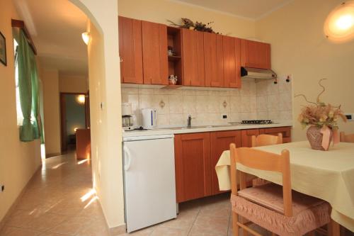 a kitchen with a table and a white refrigerator at Apartments with a parking space Tar, Porec - 7026 in Tar