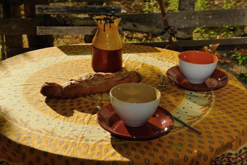 a table with two cups and a bottle on it at Gîtes Domaine des Machottes in Grans