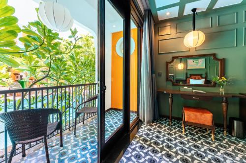 a room with a balcony with a desk and a mirror at Son Hoi An Boutique Hotel & Spa in Hoi An