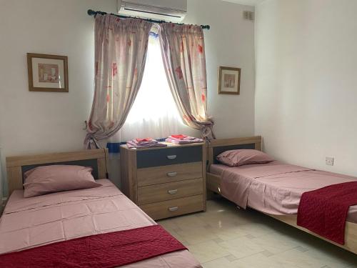 two beds in a room with a window at Sea front apartment at Mellieha Bay, Malta! in Mellieħa
