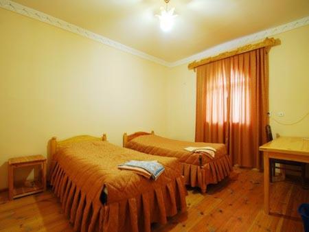 a bedroom with two beds and a desk and a window at Islambek Hotel & Travel in Khiva
