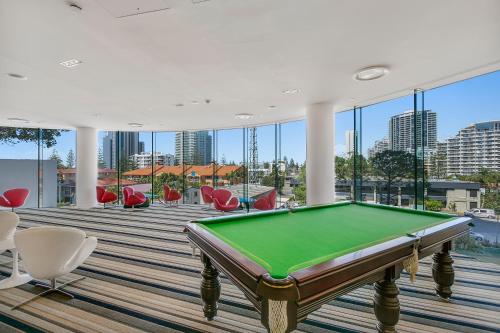 a pool table in the middle of a room with windows at Oracle Resort - Q Stay in Gold Coast