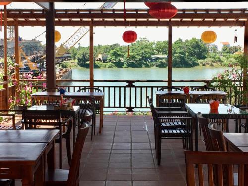 a restaurant with tables and chairs and a view of a river at Villa Orchid Garden Riverside Hoi An in Hoi An