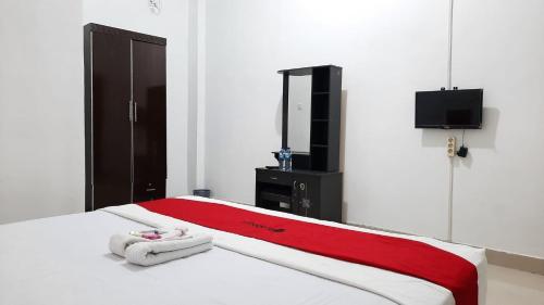 um quarto com uma cama com um cobertor vermelho e branco em RedDoorz @ Gerson Hotel Abepura em Tobadi