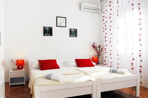 2 Betten in einem weißen Zimmer mit roten Kissen in der Unterkunft Rooms by the sea Split - 6973 in Split