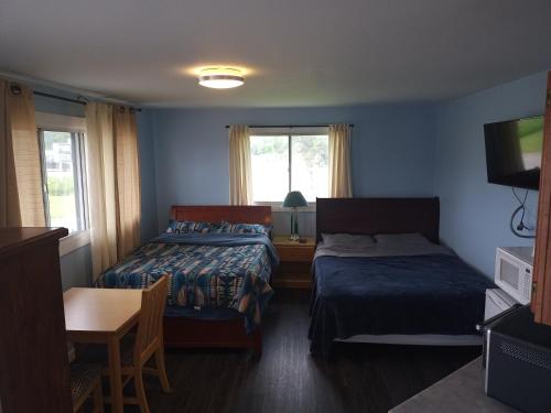 1 dormitorio con 2 camas, mesa y TV en Park Side Motel, en Peterborough