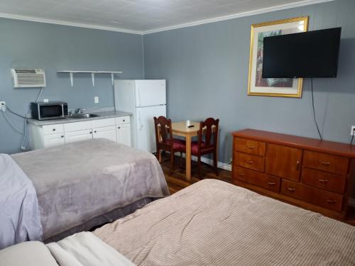 1 dormitorio con 2 camas y cocina con mesa en Park Side Motel en Peterborough