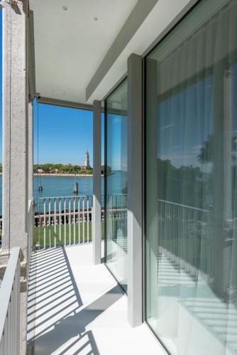 a balcony with glass doors and a view of the water at Ca' delle Contesse - Villa on lagoon with private dock and spectacular view in Venice-Lido