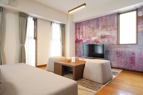 a bedroom with a bed and a tv and a table at Dio Higashi Shinsaibashi in Osaka