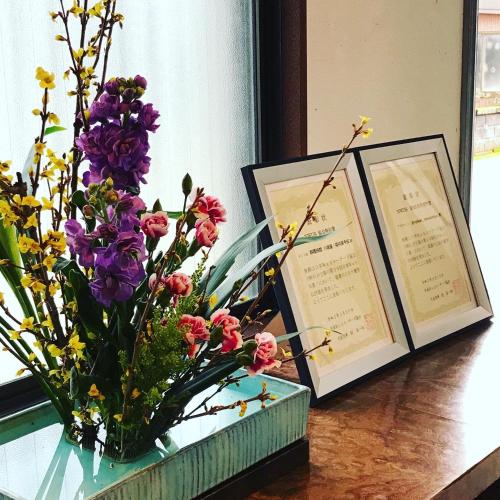 a vase of flowers on a table with two pictures at 川端屋　kawabataya in Minamiechizen