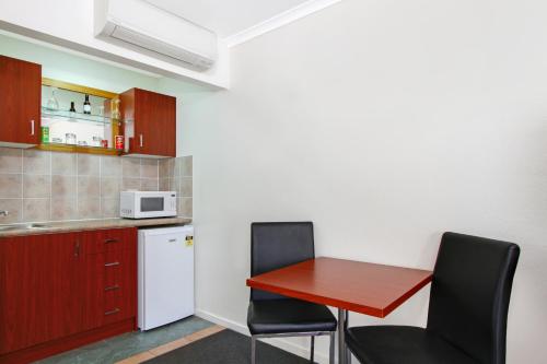 a small kitchen with a red table and chairs at Thunderbird Motel Yass in Yass