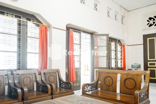 two wooden chairs in a room with windows at PKPN Syariah Boyolali Mitra RedDoorz in Mojosongo