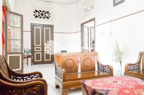 a living room with two benches and a table and a door at PKPN Syariah Boyolali Mitra RedDoorz in Mojosongo
