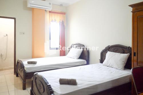 two beds in a small room with a window at PKPN Syariah Boyolali Mitra RedDoorz in Mojosongo