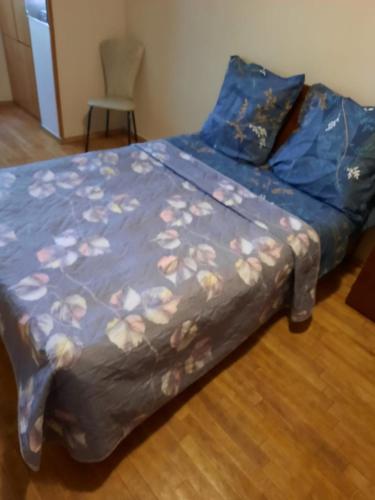 a bed with a blue comforter on top of it at Квартира проспект Церетели in Tbilisi City