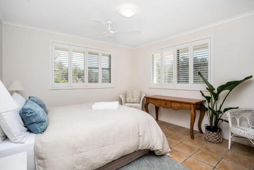 a bedroom with a bed and a desk and windows at Summer Salt in Byron Bay