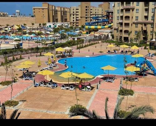 ein großer Pool mit Sonnenschirmen und ein Resort in der Unterkunft اكوا فيو الساحل الشمالى - مصريين فقط in El-Alamein