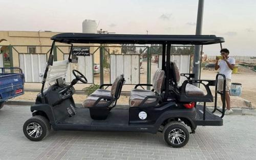 a golf cart with a man standing next to it at اكوا فيو الساحل الشمالى - مصريين فقط in El Alamein