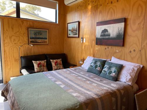 um quarto com uma cama com paredes de madeira e uma janela em Glenwai em Motueka