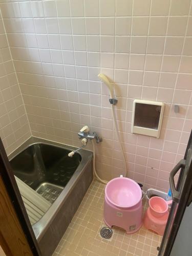 a bathroom with a bath tub and a pink toilet at Holiday Cottage BANSHIRO in Setouchi