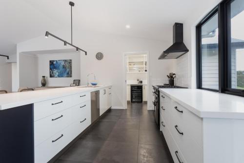 a kitchen with white cabinets and a large window at Vancouver's End by the BnB Collection in Albany