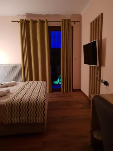 a bedroom with a bed and a television and a window at Mondeus Inn Luxury in Deskáti