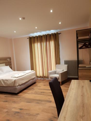 a bedroom with a bed and a chair and a table at Mondeus Inn Luxury in Deskáti