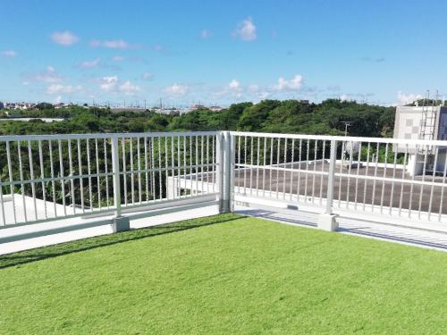 a balcony with green grass and a white fence at Room Biotop YOMITAN in Yomitan
