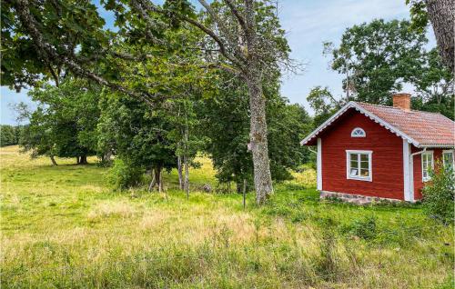 a small red house in a field with trees at Amazing Home In Tjällmo in Finspång