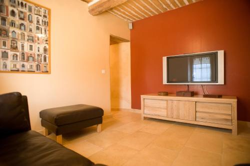 a living room with a flat screen tv on a wooden cabinet at Gîtes Domaine des Machottes in Grans