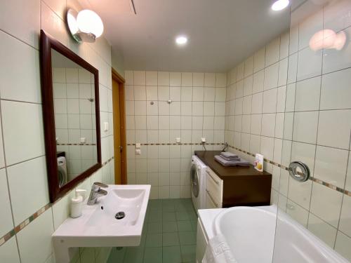 y baño con lavabo, bañera y espejo. en Cozy Foorum Apartment - Tallinn City Centre, en Tallin