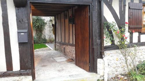 an open door of a house with a cat sitting inside at La Porterie face à l'abbaye in Le Bec-Hellouin