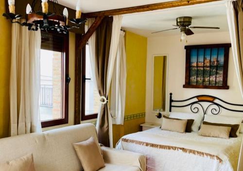a bedroom with two beds and a couch and a window at Hotel Hospederia Zacatin in Alcalá la Real