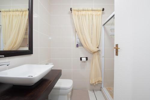 a bathroom with a sink and a toilet and a mirror at LA CRETE SANDS NO 1 in Margate