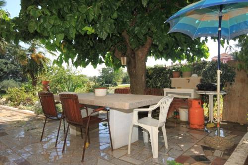 a table and chairs under a tree with an umbrella at Apartment Basanija 7149b in Savudrija
