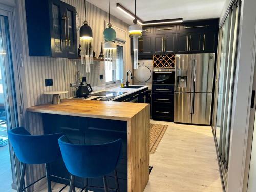 a kitchen with black cabinets and blue bar stools at Luxury open-space apartments by the sea in Ashdod