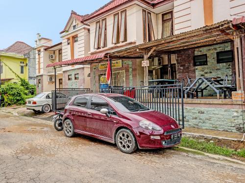 une voiture rouge garée devant une maison dans l'établissement OYO 91636 Kak Dadut Homestay, à Batam Center