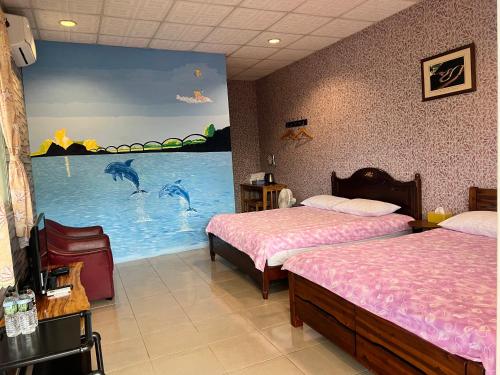 a bedroom with two beds and a large painting of dolphins at Golden flower Homestay in Yuli