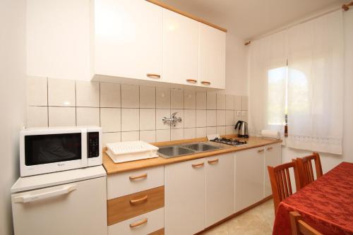 cocina con armarios blancos y microondas en Apartments with a parking space Fazana - 7153 en Fažana