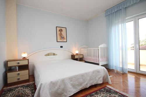 biała sypialnia z łóżkiem i łóżeczkiem dziecięcym w obiekcie Apartments with a parking space Umag - 7147 w mieście Umag