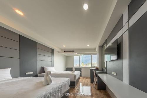 a bedroom with two beds and a television in it at The Ring Border in Ban Khlong Phruan