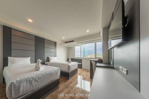 a hotel room with two beds and a flat screen tv at The Ring Border in Ban Khlong Phruan
