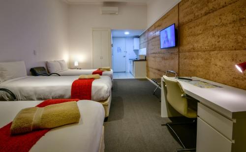a hotel room with three beds and a television at Crossroads Ecomotel in Port Augusta