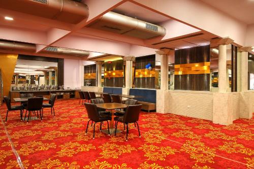 a dining room with tables and chairs on a red carpet at Hotel Mumbai House Juhu, Santacruz West, Mumbai in Mumbai