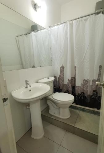 a white bathroom with a toilet and a sink at La Casona Hospedaje in Lima