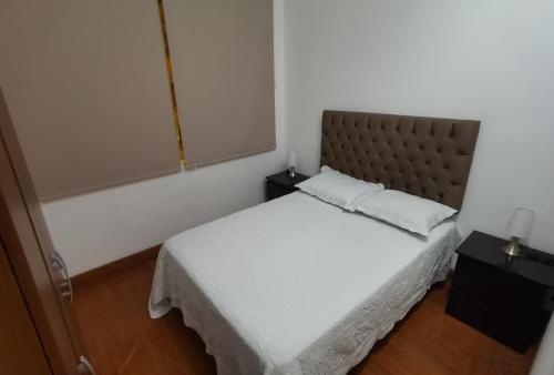a bedroom with a white bed with a brown headboard at La Casona Hospedaje in Lima