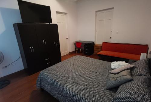 ein Schlafzimmer mit einem Bett, einer Kommode und einer roten Bank in der Unterkunft La Casona Hospedaje in Lima