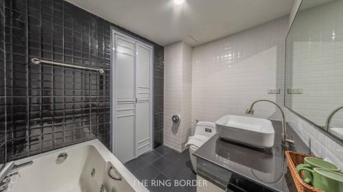 a bathroom with a sink and a toilet and a tub at The Ring Border in Ban Khlong Phruan